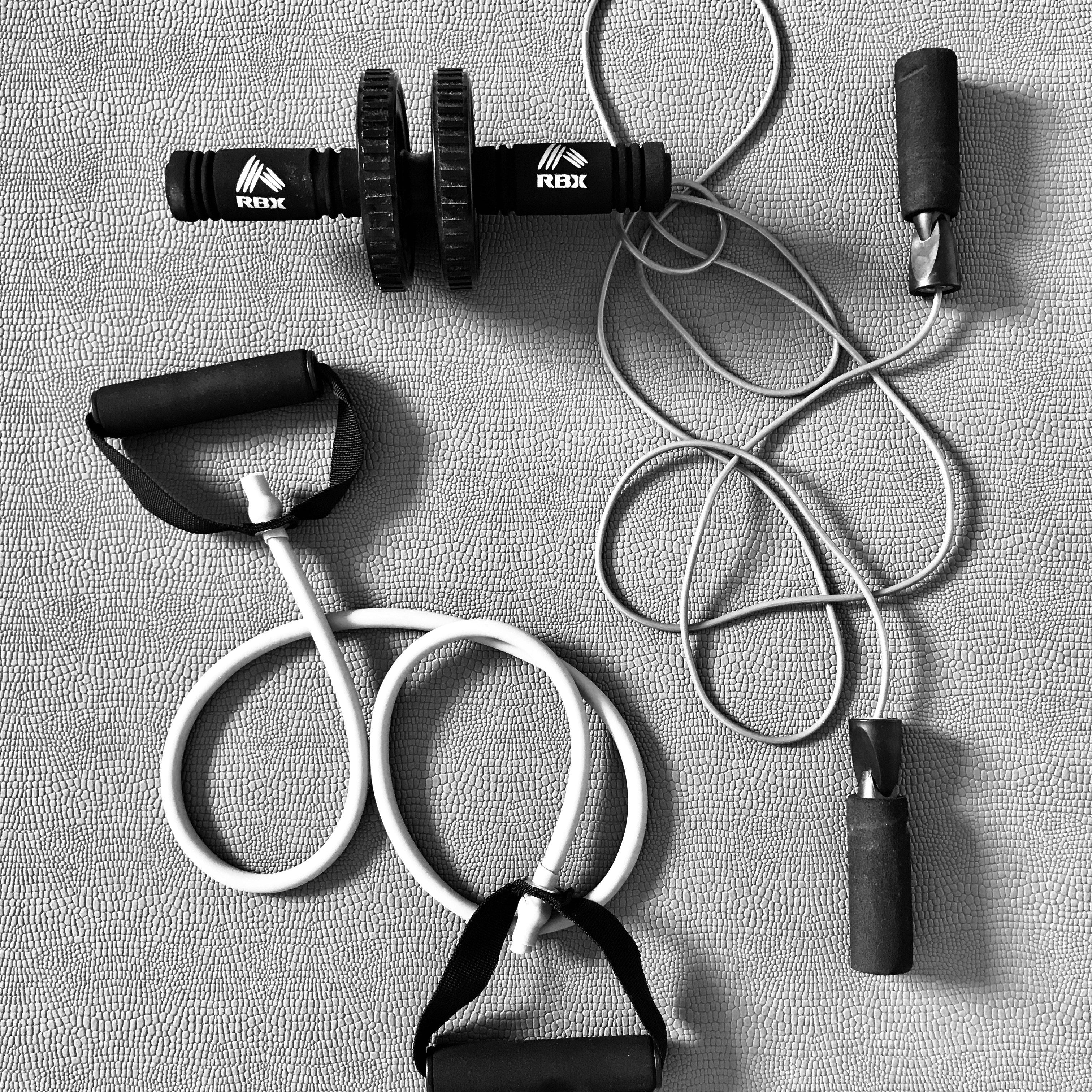 Set of fitness equipment including dumbbells, resistance bands, and a jump rope on a gray surface.